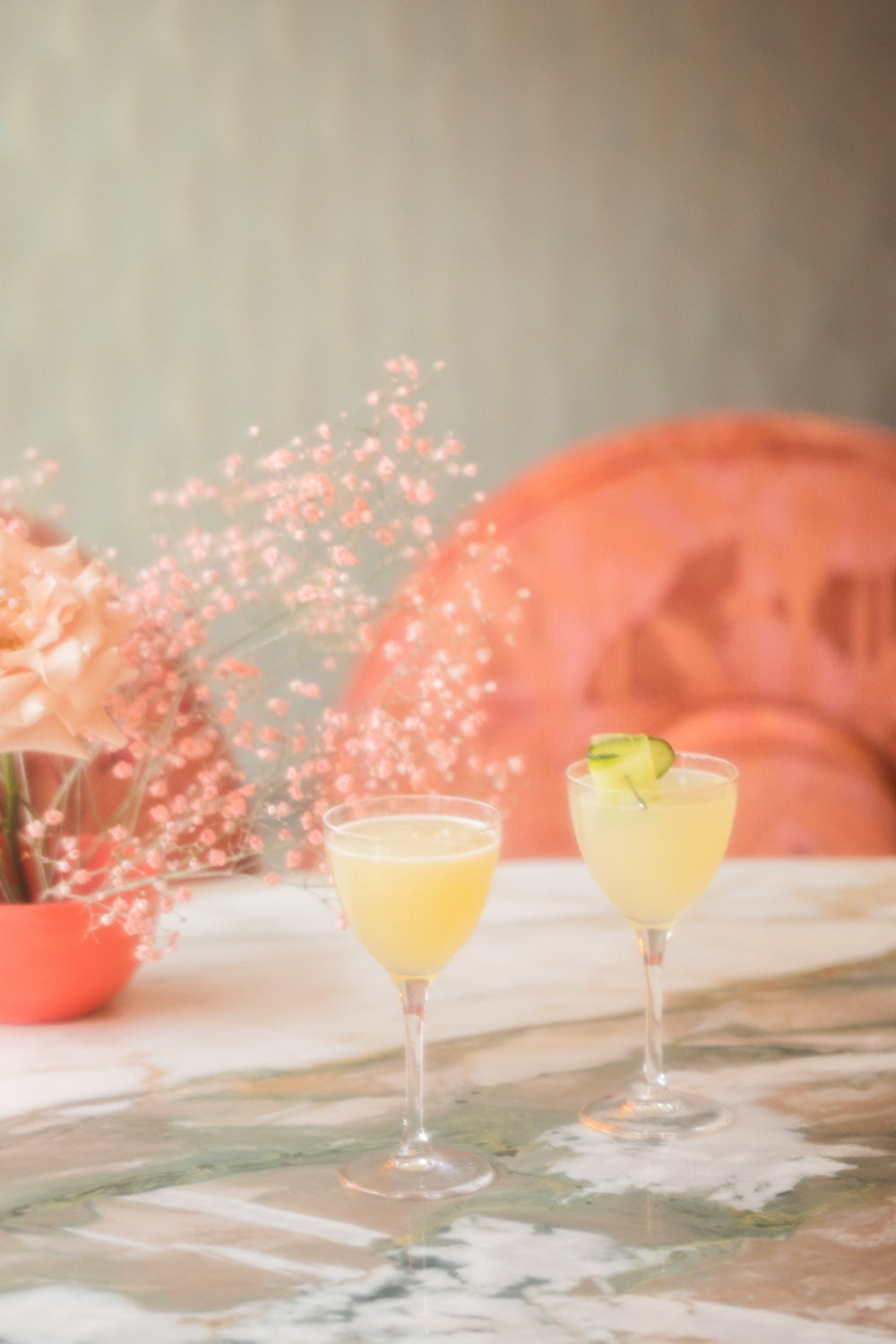 Cocktail e fiori su un tavolo di marmo tra le poltroncine rosa di The Appuntamento